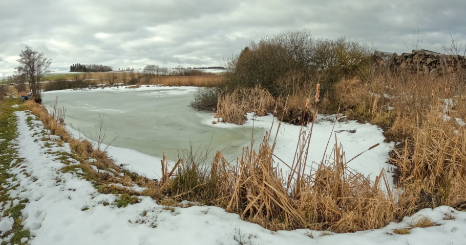Timelapse, mooving clouds over small frozen pond. Czech highland vysocina european countryside