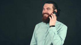 Close up video of happy young man talking on smartphone over dark background and smiling