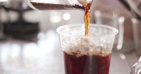 Pour the americano coffee into the iced glass. Freshly brewed coffee mixed with ice cubes in glass.