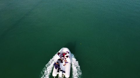 Phuket, Thailand, 22, January, 2022:
The yacht club staff moves across the sea on a motorized inflatable boat, a drone view of people in dinghys
