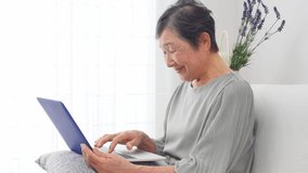 Asian senior woman using the laptop at home