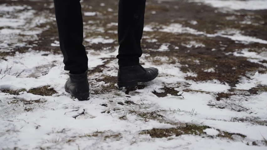 Musician in black tailcoat goes to musical instrument, piano, on cliff above the ocean in winter. Snow covered earth
