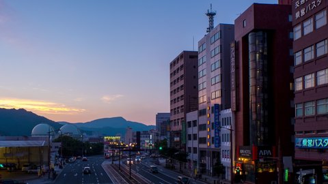 NAGASAKI, JAPAN - 28 JULY 2018: Aerial view of lively center in Nagasaki, Japan in the evening car and people traffic. Time-lapse during the sunset, panning video