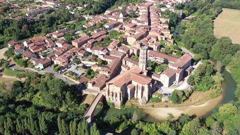 Scenic aerial view of Rieux-Volvestre town on banks of small tributary of Garonne in summer overlooking ancient Roman Catholic Cathedral, France