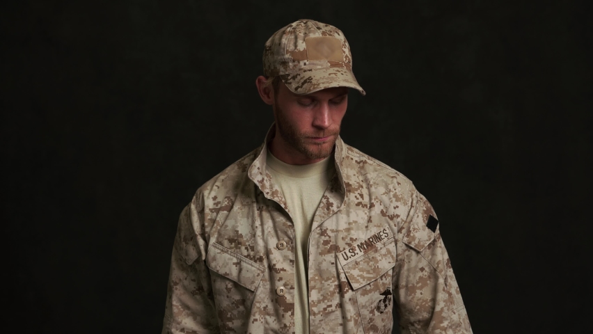 Serious military man writing something on tablet in black studio