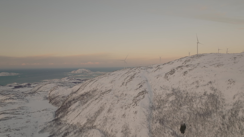 Wind turbines on snowy island with sea. Windmill. Renewable and Green energy.