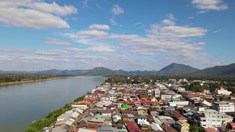Aerial footage sliding towards the left revealing the rooftops of the building at the Walking Street and Mekong River then across is Laos, Chiang Khan, Loei in Thailand.