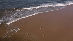 Children playing on beach shore, Playa Grande at Punta del Diablo in Uruguay. Aerial top-down circling