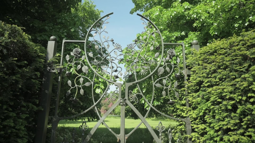 High angle walking back from a metal gate dividing two different gardens.