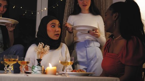 African american girl showing her wedding ring to her female friends during dinner in the evening, beautiful young women are surprised and amazed. Happy girls celebrate friendship, have party
