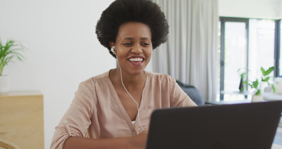 Happy african american woman sitting at table using laptop. domestic lifestyle, spending free time at home.