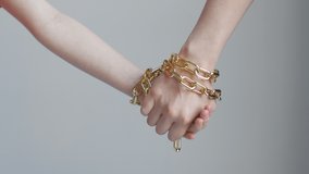 A woman and a child hands are tied with a golden chain, holding and not letting go - Powered by Shutterstock - Get 15% off with code: PIKWIZARD15