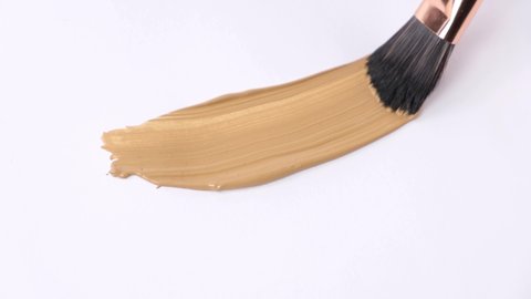 makeup brush applying concealer on the floor