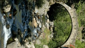Stone bridge in a river on the mountains of Pyrenees.Video in vertical format.Front view of a small stone bridge of Romanic style of thirteenth century, in the town of  Tavascan, Catalonia, Spain.