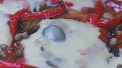 Knife cuts appetizing pizza with baked cheese and black olives close-up. Stuffing with pepper and capers. National Italian dish. World Cuisine