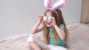 Happy blonde girl with bunny ears plays with Easter eggs and laughs. Easter preparation. Easter symbols.