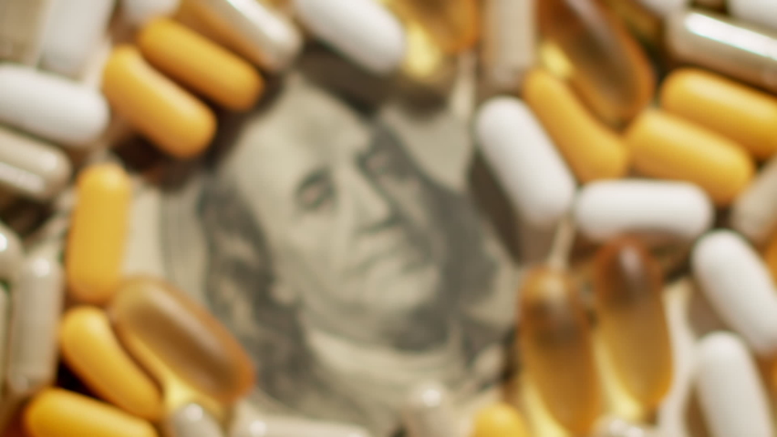 Medical pills lying on US Dollar Bill, From blurry to focused. Big pharma conspiracy theory concept | Shutterstock HD Video #1087380950