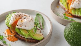 Avocado toast with poached egg over rye bread toast with soft cheese and sprouts. Healthy breakfast