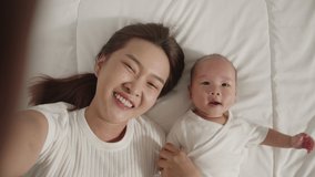 Point of view, young Asian mother and her newborn baby selfies with smile via video call feeling happy