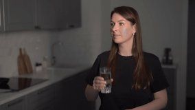 A young woman is holding a glass of clean water. The girl drinks water. Person in the kitchen, healthy eating, diet. Health care, water balance. - Powered by Shutterstock - Get 15% off with code: PIKWIZARD15