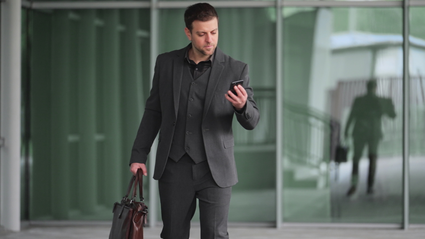 Charming Man in Balck Suits Talking on Phone walking with briefcase in hand Royalty-Free Stock Footage #1087404620