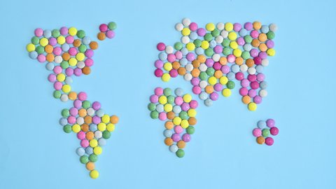 6k Sweet colorful candies make Earth map on bright blue background. Stop motion flat lay concept	
