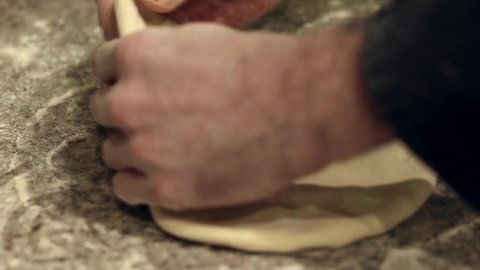 Pizzaiolo kneads, stretching a piece of dough. Pizza dough. The chef prepares pizza in a professional kitchen. Pizzeria.