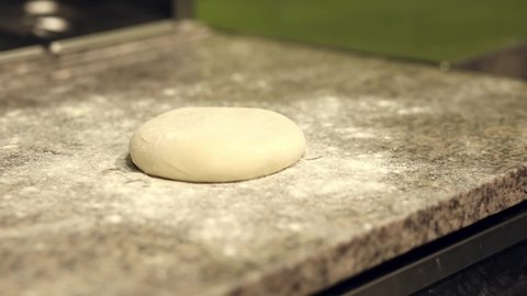Pizzaiolo kneads, stretching a piece of dough. Pizza dough. The chef prepares pizza in a professional kitchen. Pizzeria.