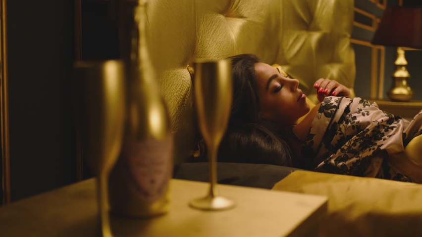 Beautiful Young Woman Sleeping Dreaming and Flirting in Bed . Female model resting lying asleep inside luxury golden bedroom . Golden room in hotel , house . Shot on ARRI cinema camera in slow motion