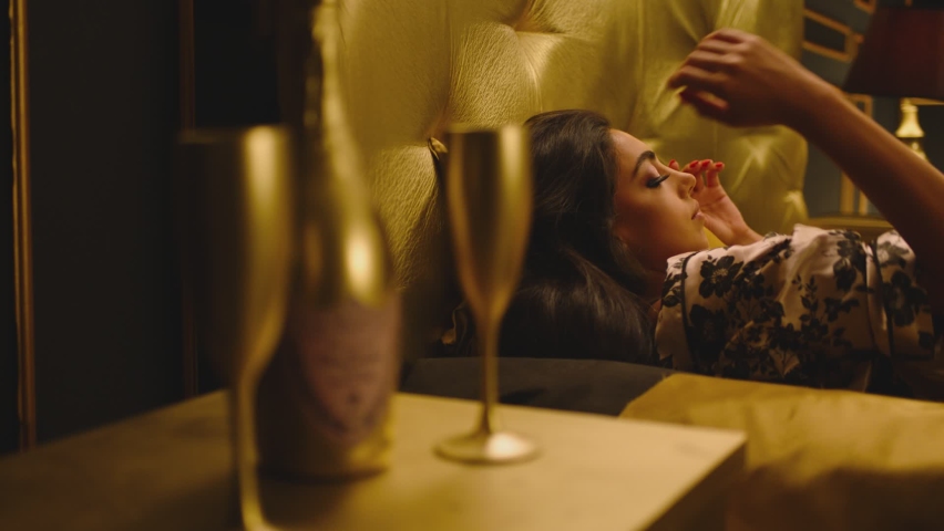 Beautiful Young Woman Sleeping Dreaming and Flirting in Bed . Female model resting lying asleep inside luxury golden bedroom . Golden room in hotel , house . Shot on ARRI cinema camera in slow motion