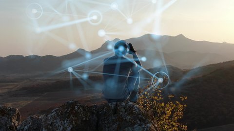 The concept of psychological training. A man sits on top of a cliff at sunset and tries to organize his thoughts. The process of concentration is visualized by means of computer graphics