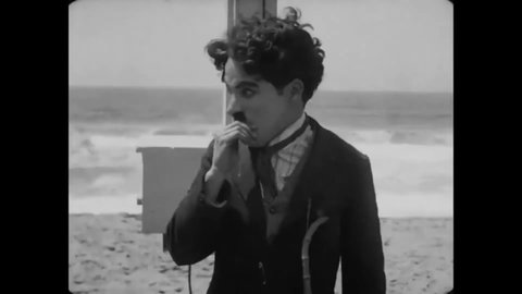 CIRCA 1915 - In this silent comedy, a man (Charlie Chaplin) fights another man on a beach and checks his hair for lice.