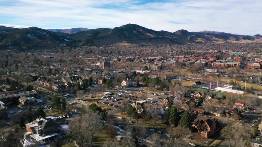COLORADO - CIRCA 2022 - aerial of the city of Boulder, Colorado and suburbs with front range of the Rocky Mountains in background, winter.