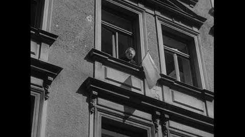 CIRCA 1945 - White flags of surrender hang from windows in a German town.