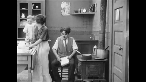 CIRCA 1914 - In this silent comedy, a man (Charlie Chaplin) tries to handle a burning stove and fussy baby in the kitchen.