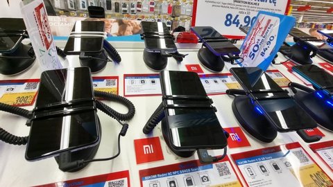 Krakow, Malopolska, Poland - January 2022: Lots of different smartphones, mobile phones on a store display, Auchan supermarket, objects closeup, pan, nobody. Selling, buying consumer grade devices