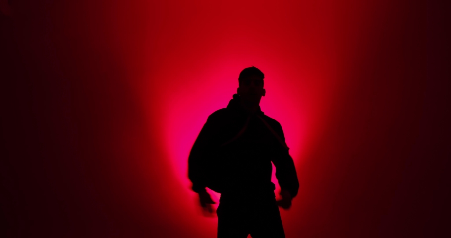 Silhouette of young man dancing in red light
