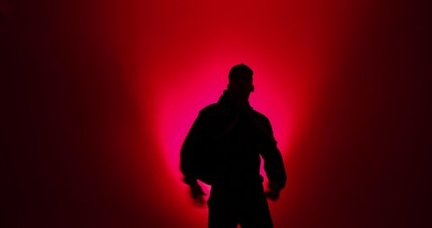 Silhouette of young man dancing in red light
