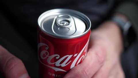WROCLAW, POLAND - FEB 22, 2022: Closeup man fingers hold open up a coca cola can drink carbonated beverage