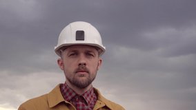 Building contractor on site concept. Correcting helmet at construction site. Serious cute caucasian bearded construction electrician, supervisor, foreman or architect. High quality 4k video footage