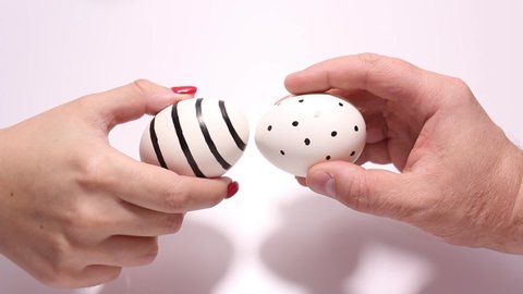 Full HD video for Easter. Russian traditional Easter game. Easter Egg Battle. A dot-patterned chicken egg in a man's hand is broken against a black-striped chicken egg in a woman's hand