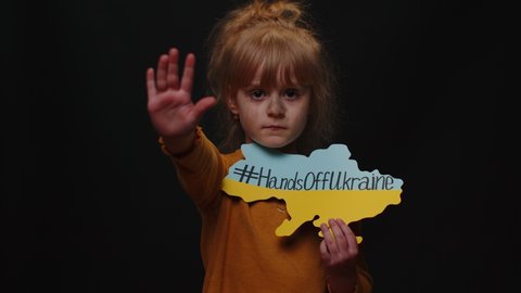 Portrait of homeless Ukrainian girl child kid in dirty torn clothes showing inscription massage text on map Hands Off Ukraine. Asking Stop aggression from Russia country. Crisis, war, no peace, help