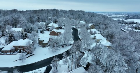 American homes in winter snow. Aerial establishing shot. Dolly forward to mountain ski town.