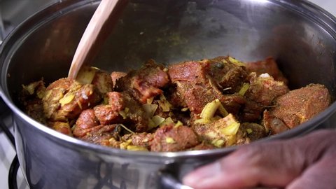 Jamaican curry goat marinated and mixed with wooden spoon.  Slow motion