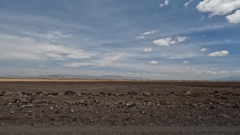 Desert fields of Africa scorched by the sun. Panorama of the vast expanses of Tanzania. African nature. Mountains, hills, blue sky and white clouds.