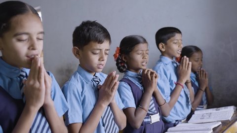Students at classroom doing morning prayer with closed eyes - concept of wisdom, friendship, development and discipline.