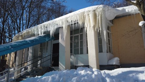 Large dangerous icicles hanging from the roof of the yellow building