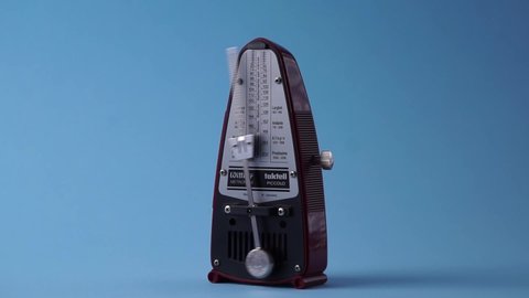 Metronome in action, isolated on a light blue background. Musical tempo marks. Serbia, Novi Sad, 26.01.2022 