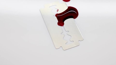 Classic razor blade with blood drops on a white background. Razor cut. Suicide.