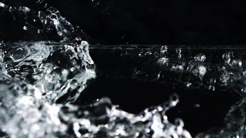 Slow motion water surface texture splash, waves and ripples on black background